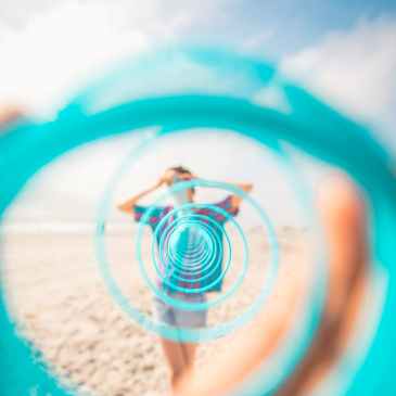 unrecognizable traveler on sandy beach in front of toy rainbow
